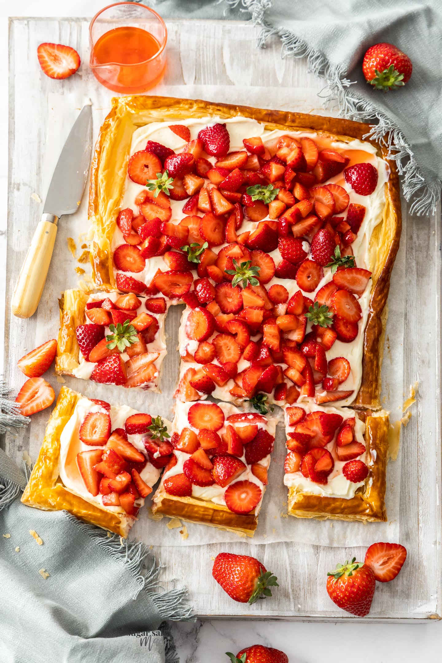 Top down view of a strawberry puff pastry tart cut into squares.