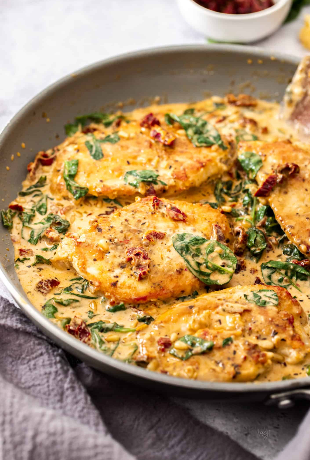 Chicken breast pieces in a skillet in sauce.