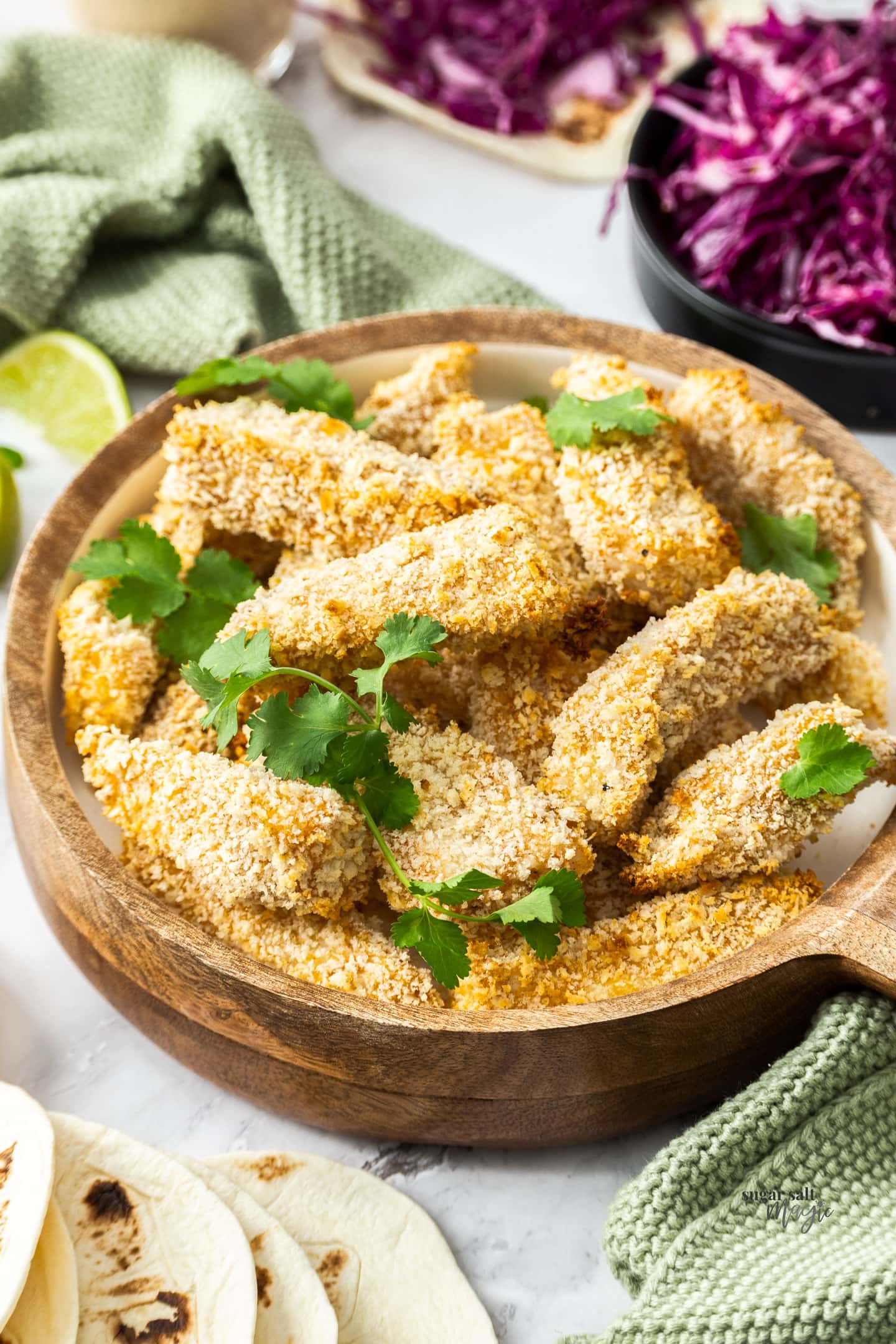 Pieces of baked crumbed fish in a wooden bowl.
