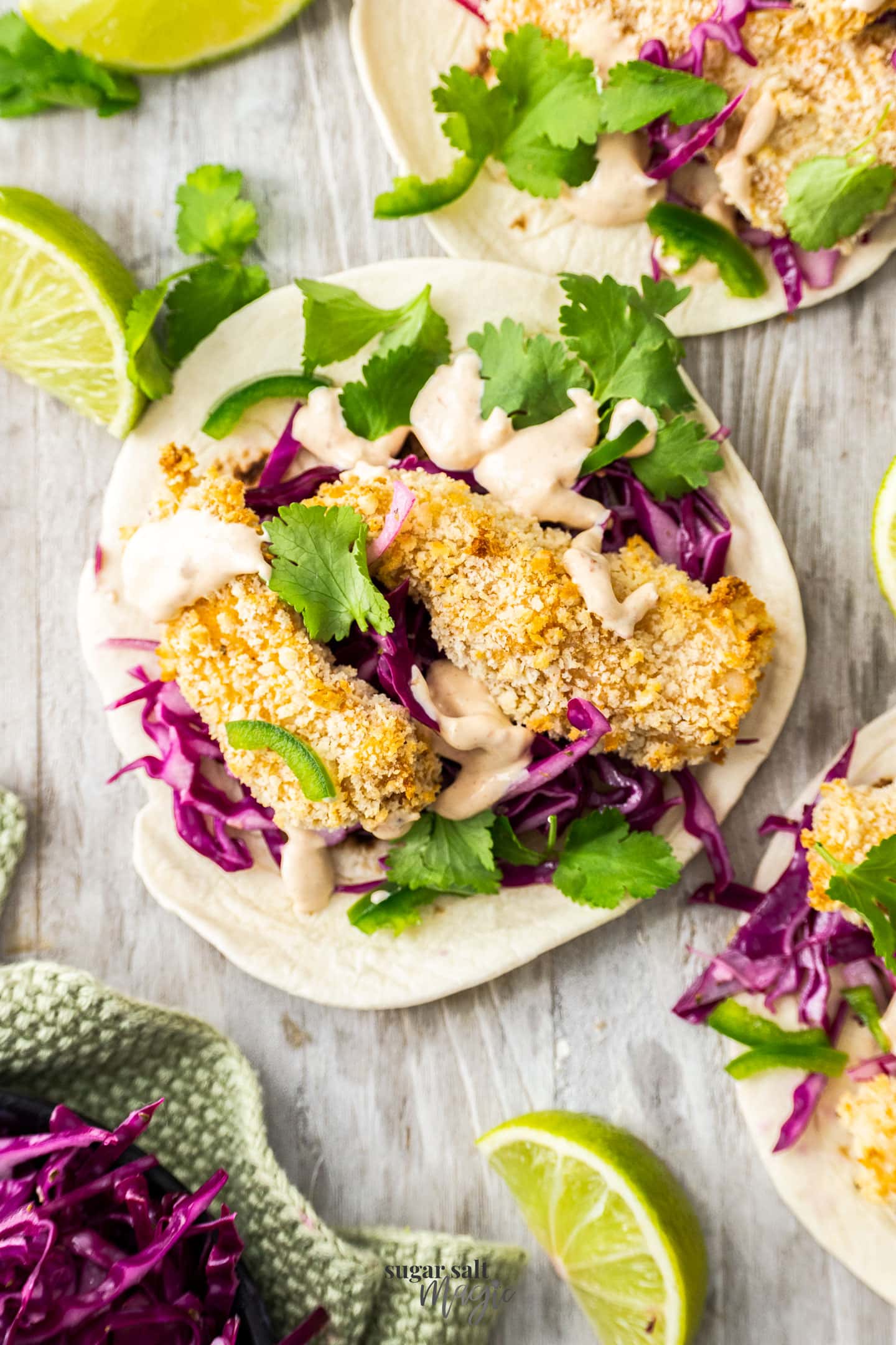 Two pieces of fish on a tortilla with cabbage and coriander.