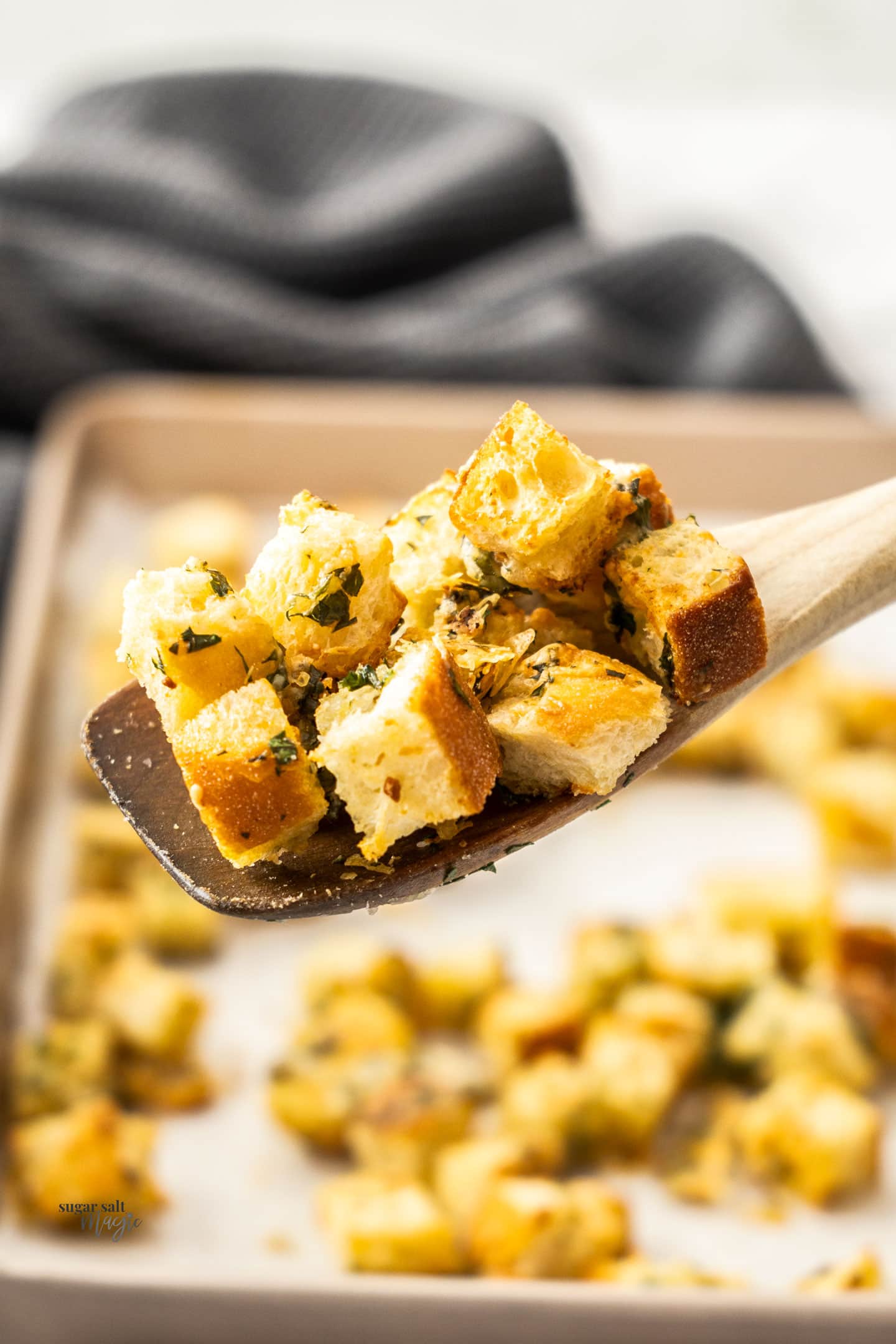 Cheese garlic croutons on a wooden spoon.