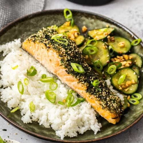 A dish filled with rice, salmon and cucumber salad.