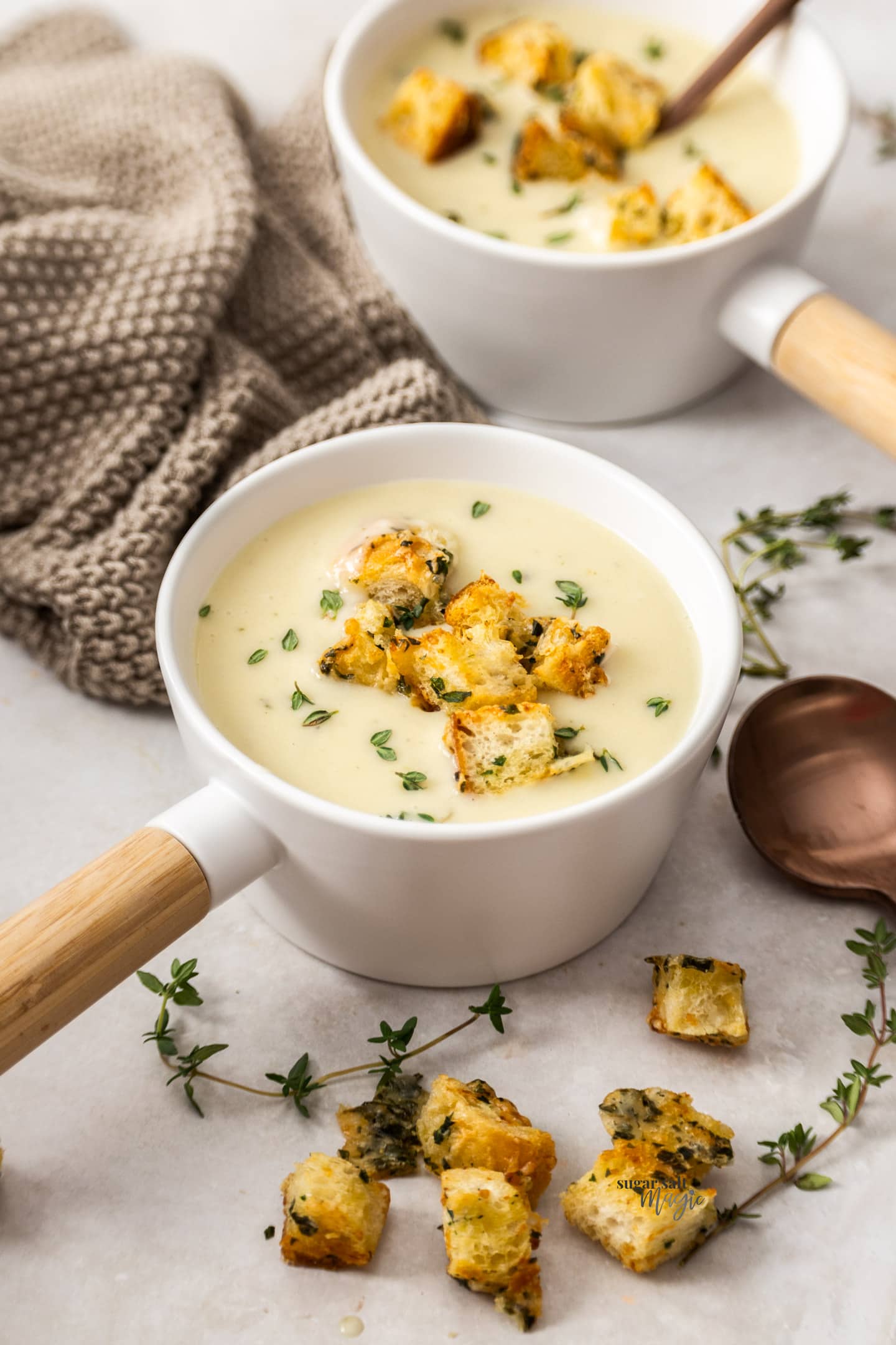 Two soup bowls filled with potato chowder and croutons.