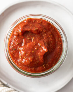 Closeup of pizza sauce in a glass jar.