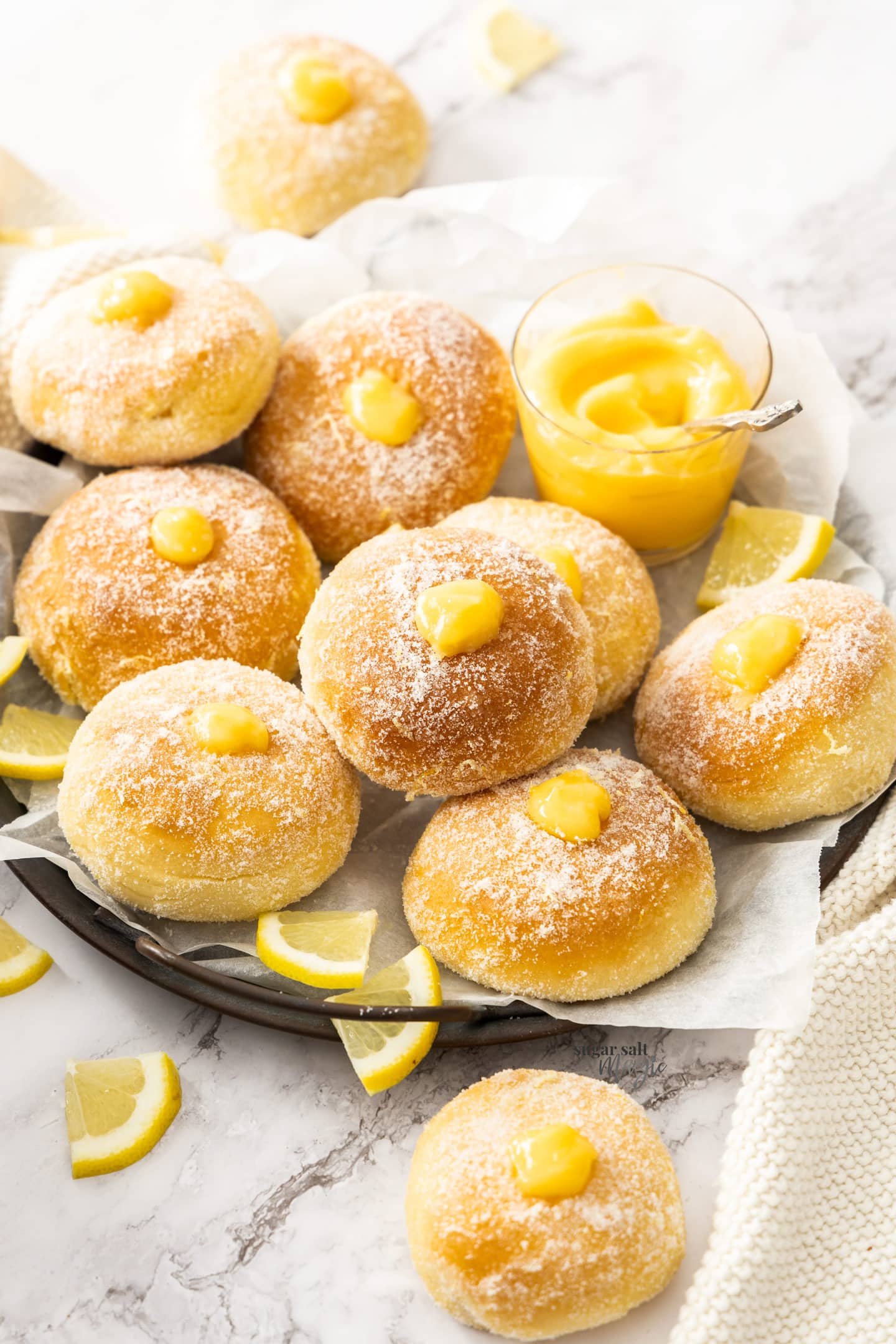 A dark tray with 10 donuts filled with lemon curd.