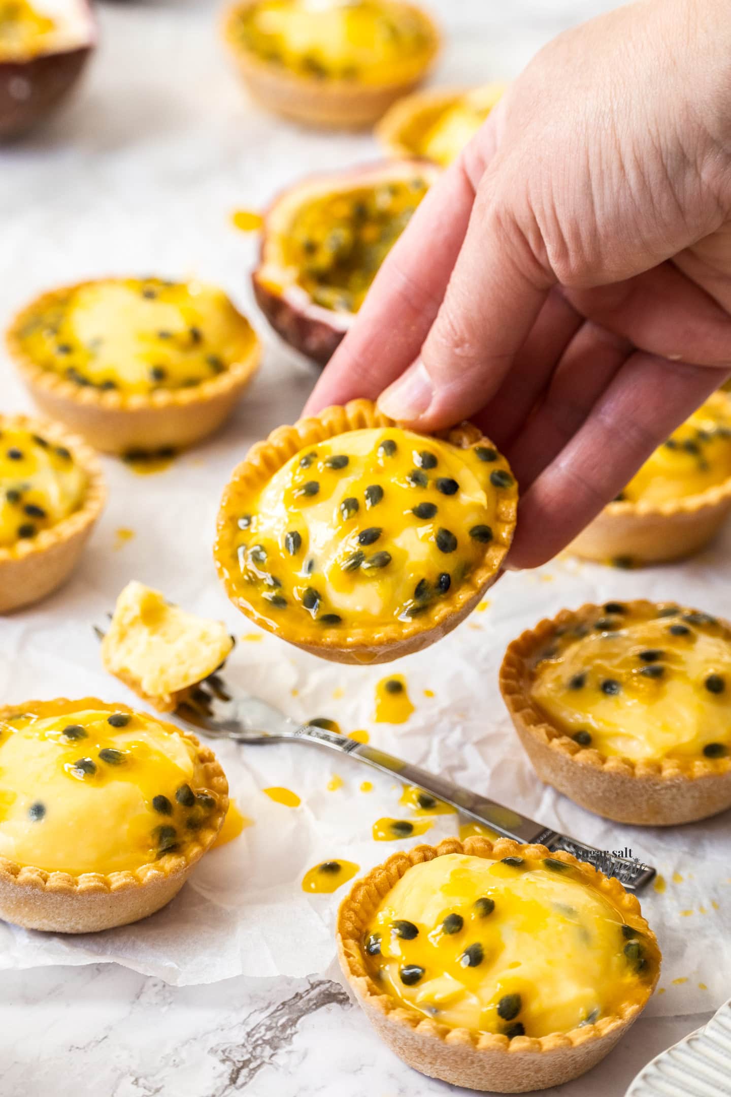 A hand holding a passionfruit tartlet.