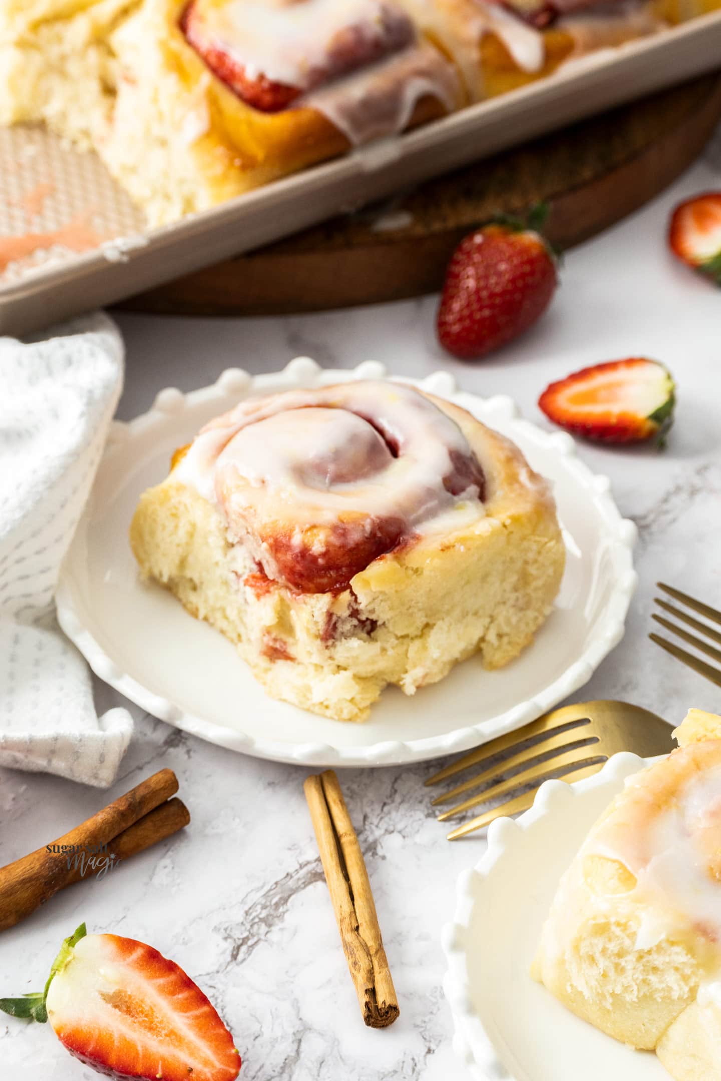 A strawberry cinnamon roll on a dessert plate.