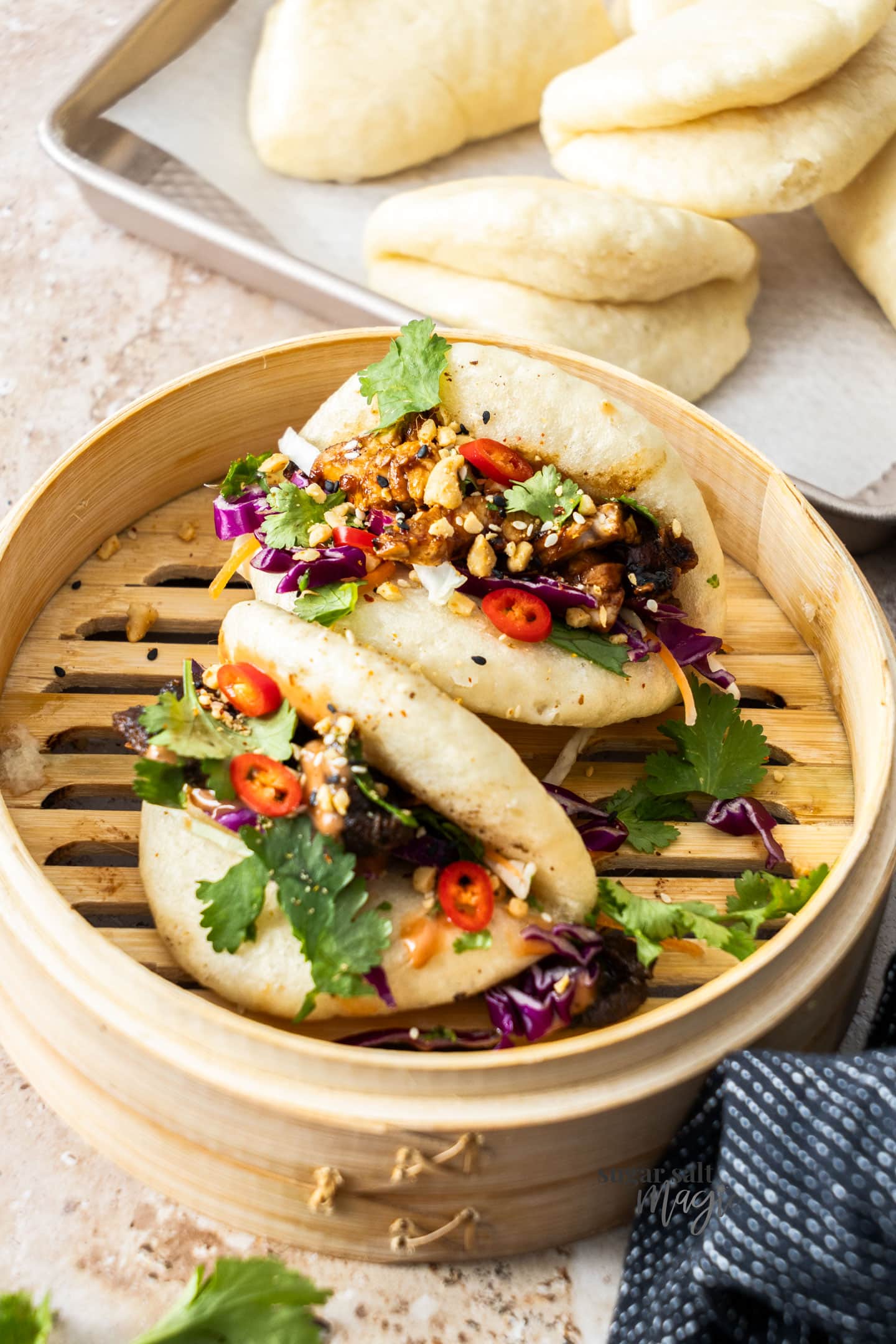 Two filled bao buns in a bamboo steamer.