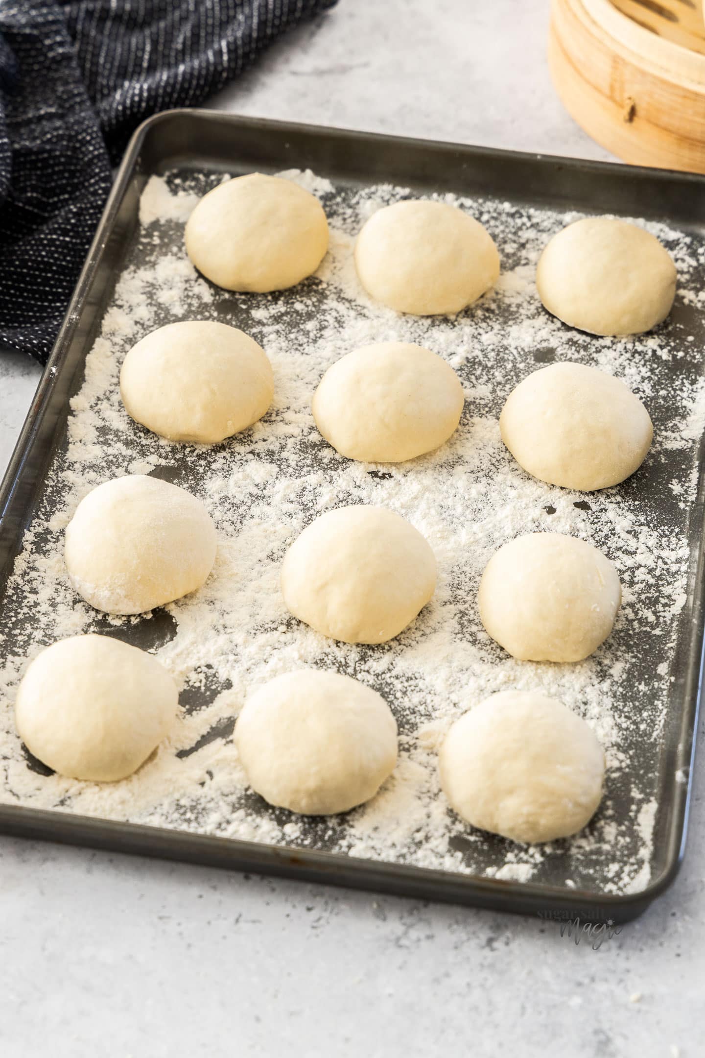 12 small balls of dough on a floured baking tray.