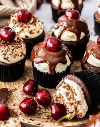 A batch of black forest cupcakes on a wooden board.
