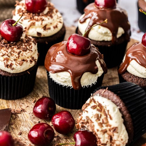 A batch of black forest cupcakes on a wooden board.