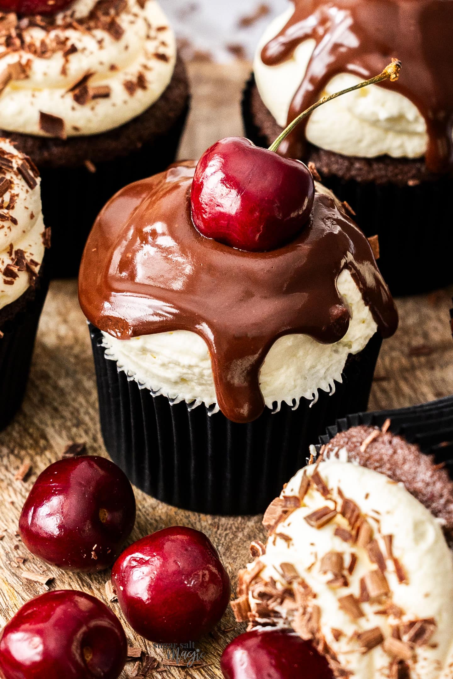 Closeup of a single cupcake with a fresh cherry on top.