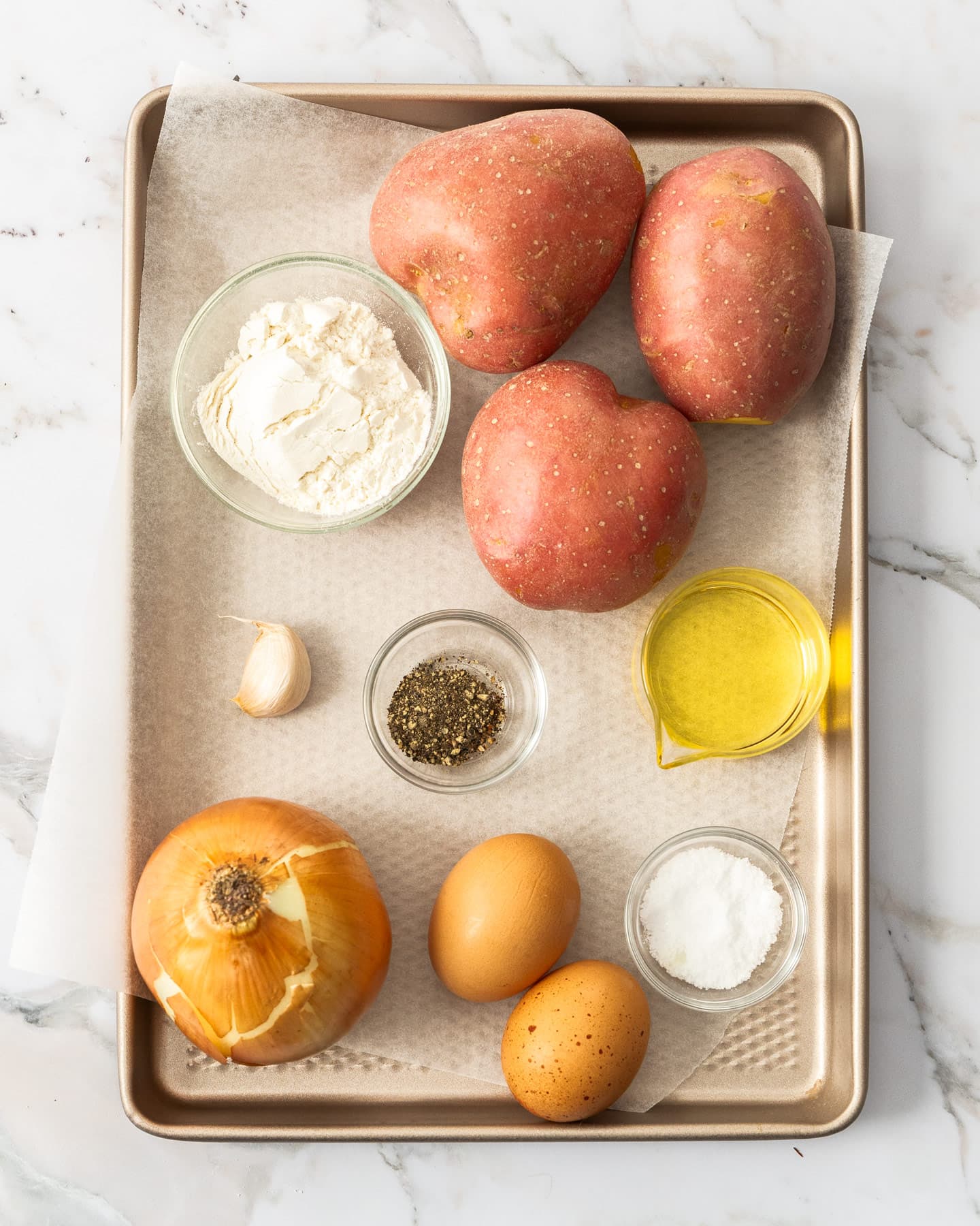 Ingredients for potato fritters on a baking tray.