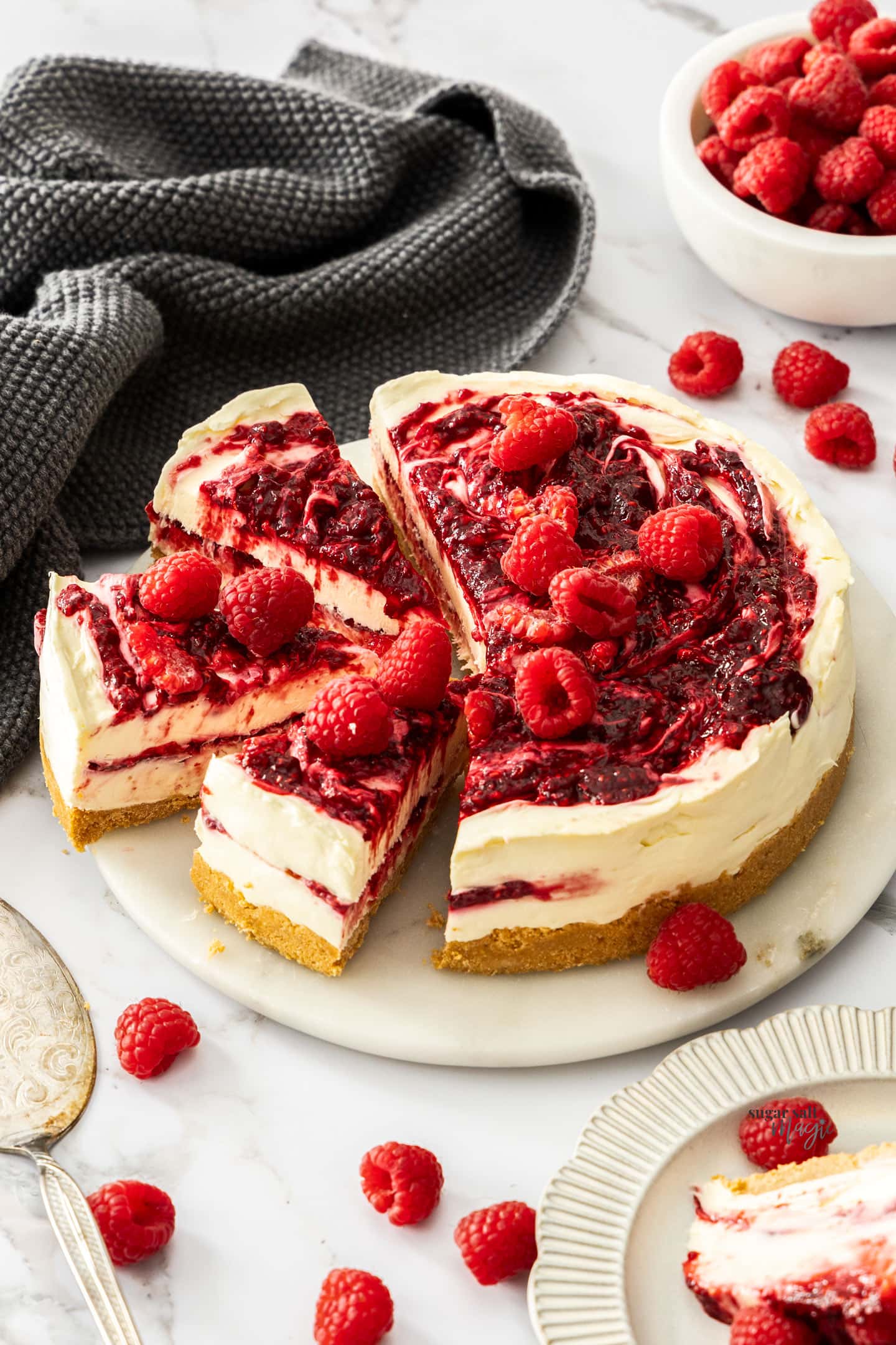 A raspberry cheesecake with 3 slices cut from it.
