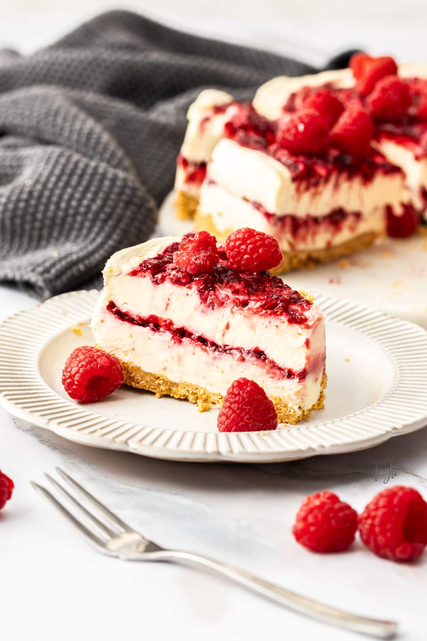 A slice of raspberry cheesecake on a dessert plate.