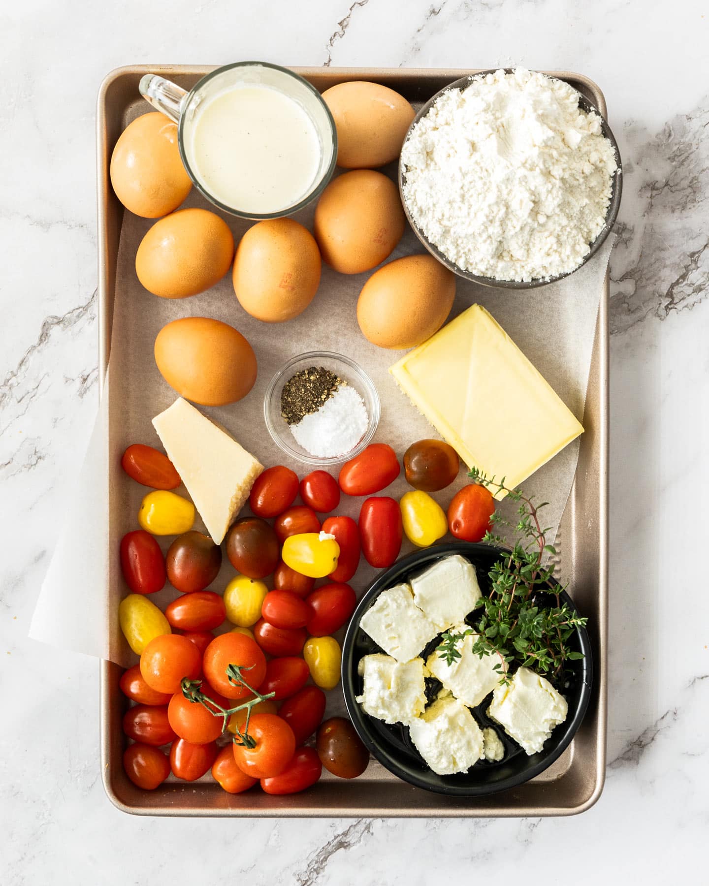 Ingredients for cheese and tomato quiche on a baking tray.