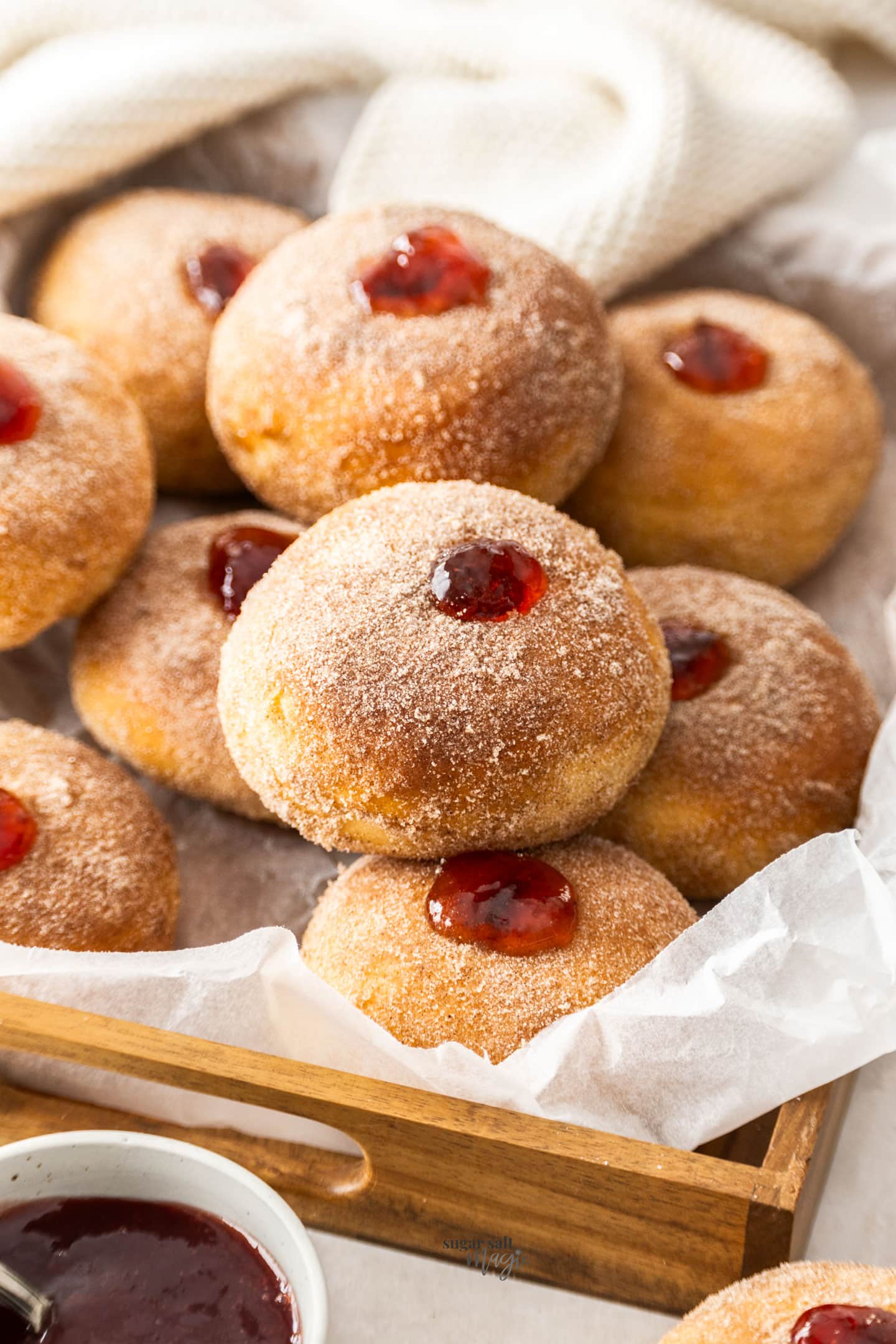 A wooden tray filled with jam doughnuts.