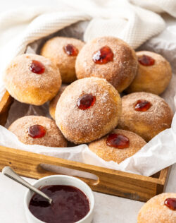 10 jam donuts in a wooden tray.