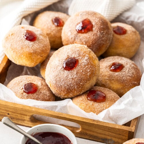 10 jam donuts in a wooden tray.