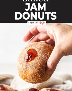 A hand holding a jam donut.
