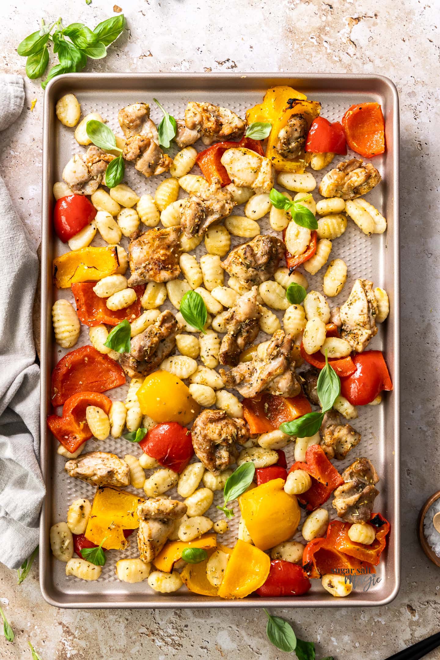 Chicken, peppers and gnocchi on a baking tray.