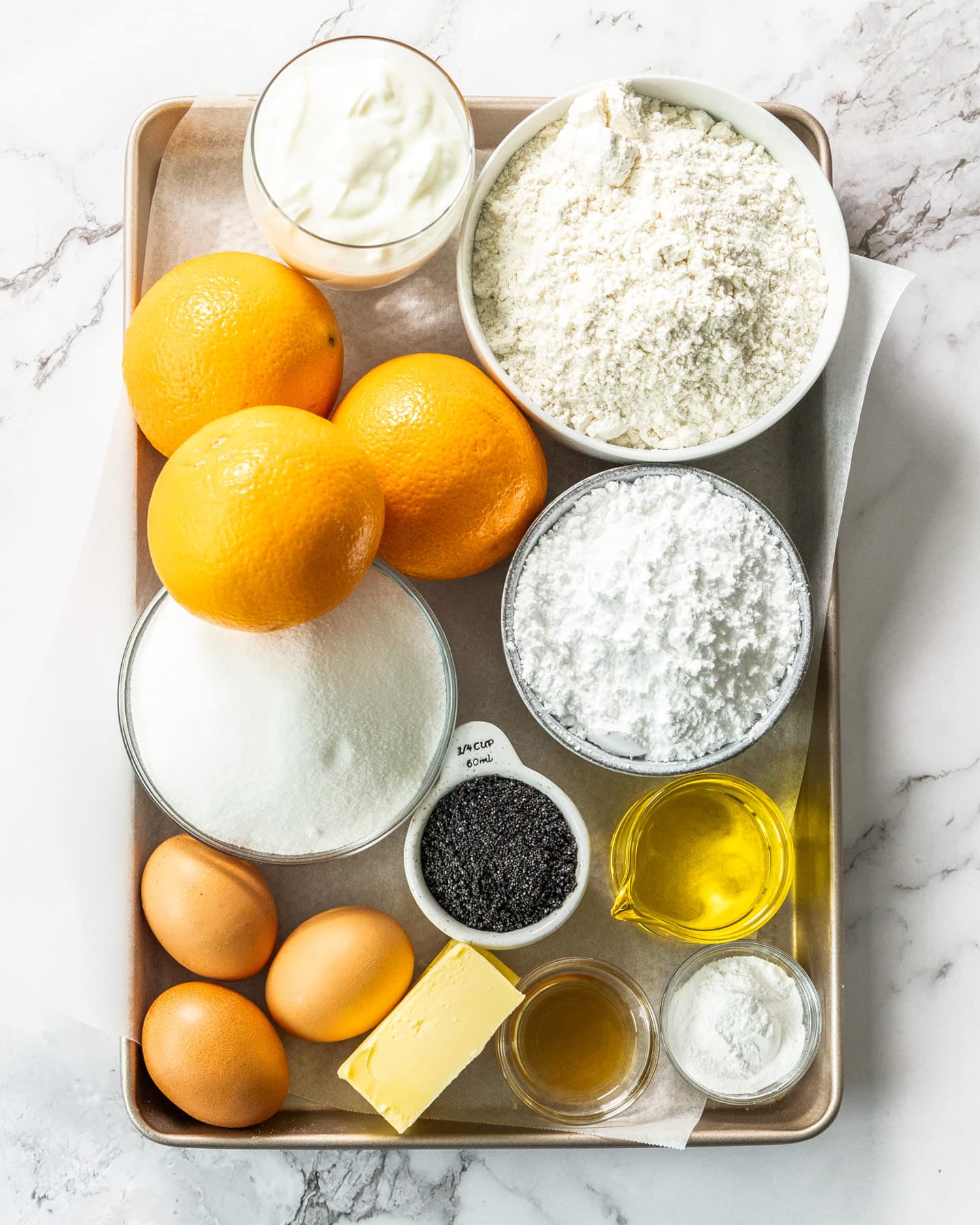 Ingredients for orange and poppy seed cake on a baking tray.