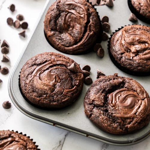 6 triple chocolate muffins with chocolate chips strew around.