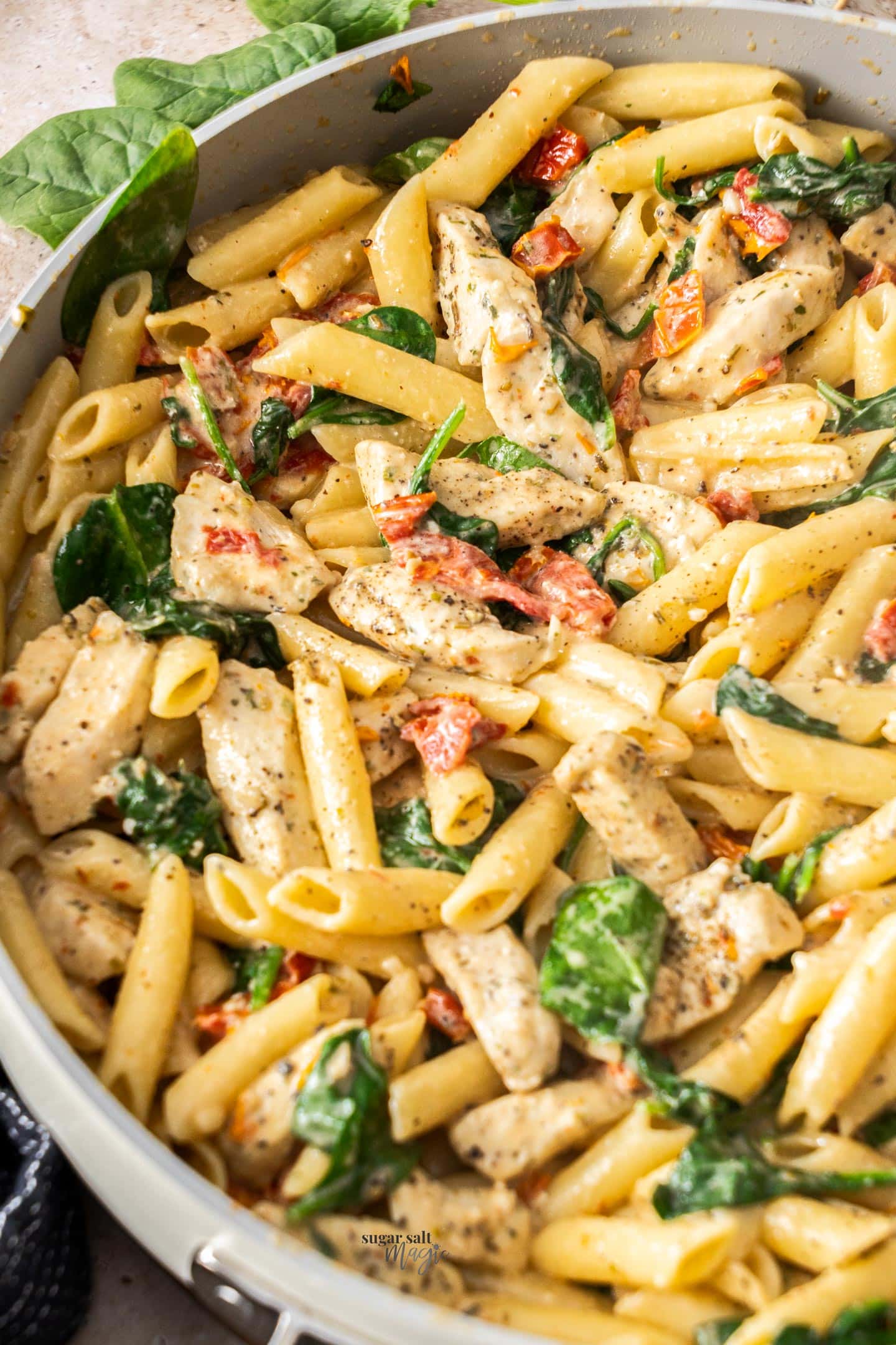 A closeup of a pan filled with cooked penne and chicken.