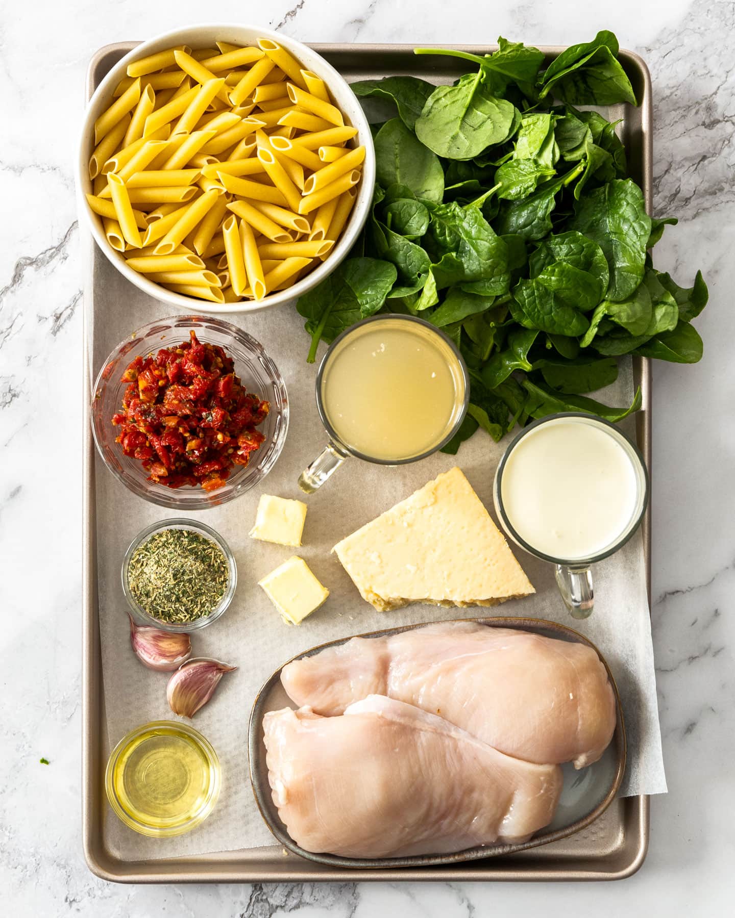 Ingredients for chicken penne pasta on a baking tray.
