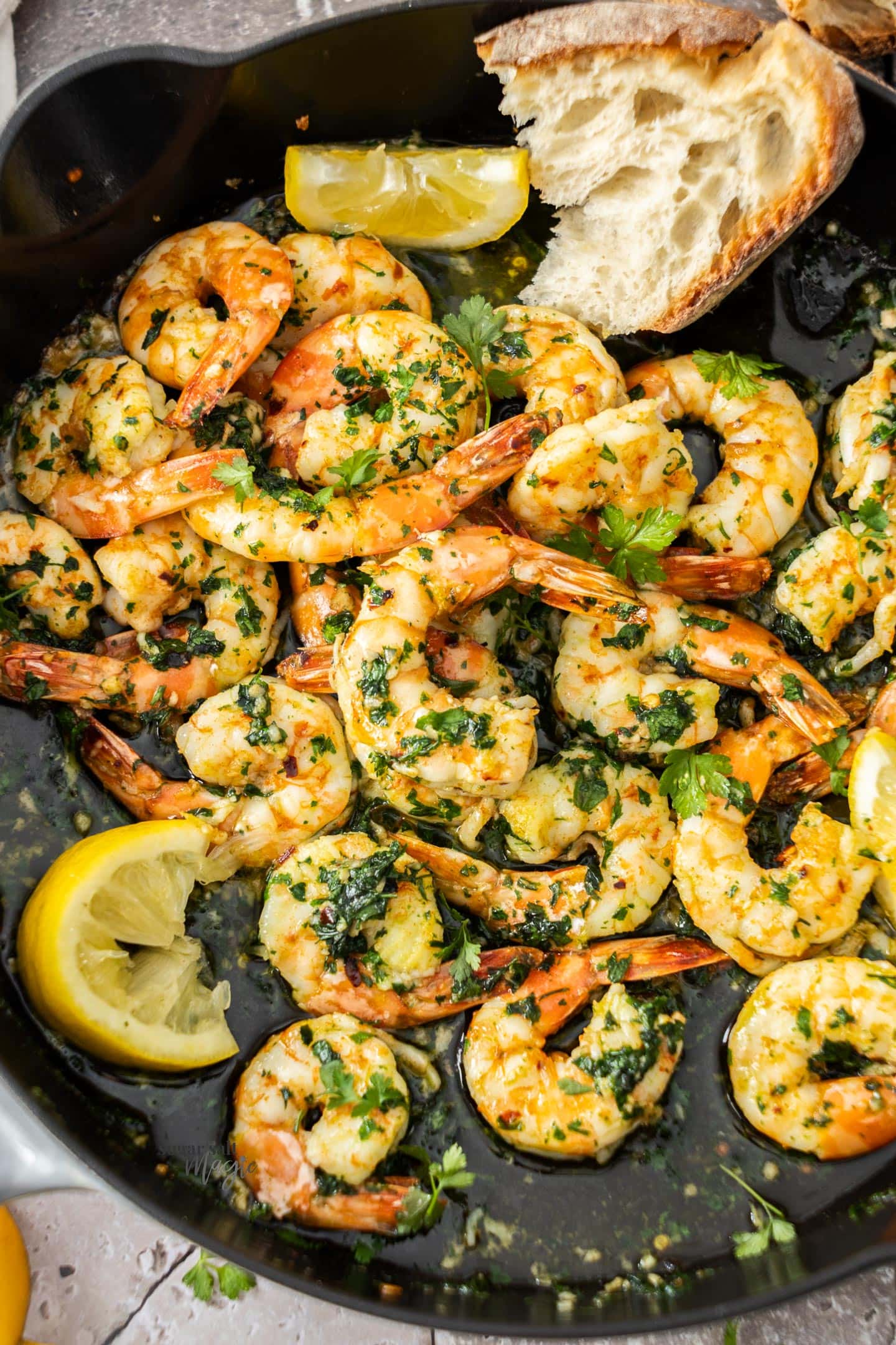 Top down view of cooked garlic prawns in a pan.