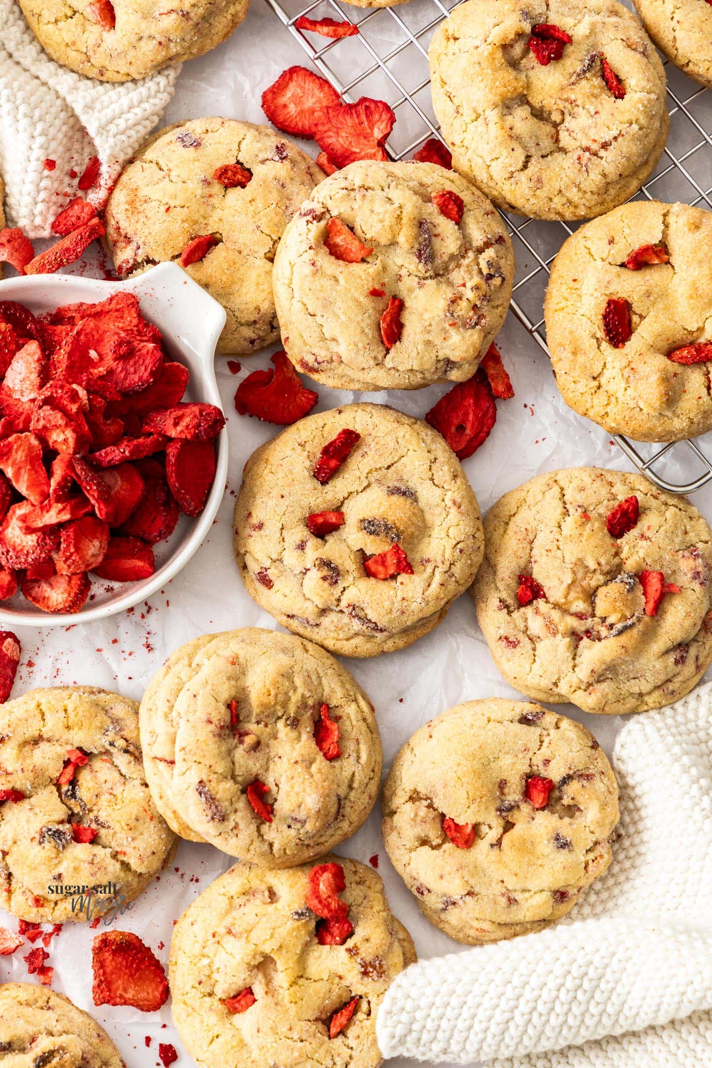 A batch of cheesecake stuffed cookies surrounded by freeze dried strawberries.