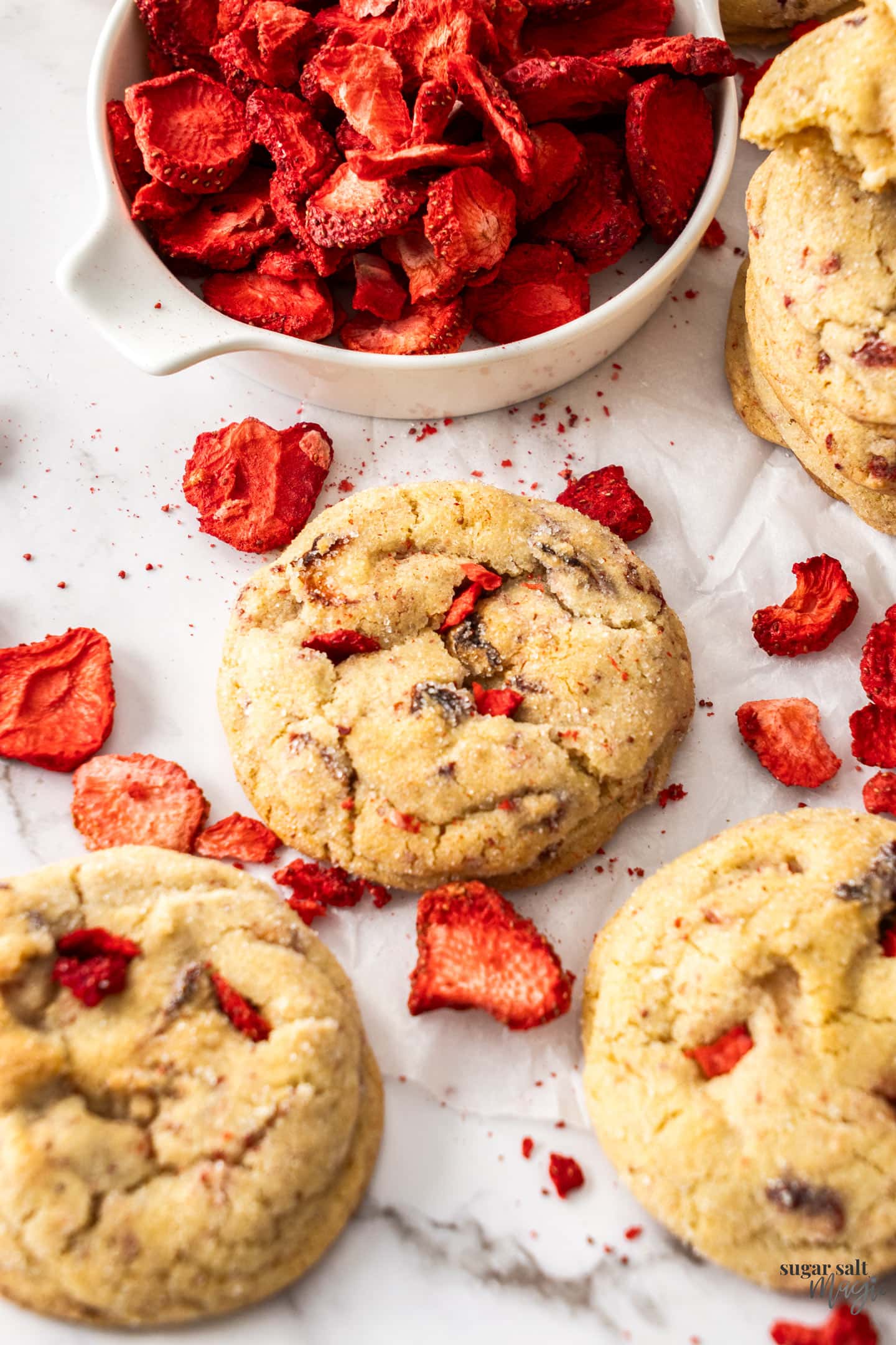 A strawberry cookie surrounded by freeze dried strawberries.