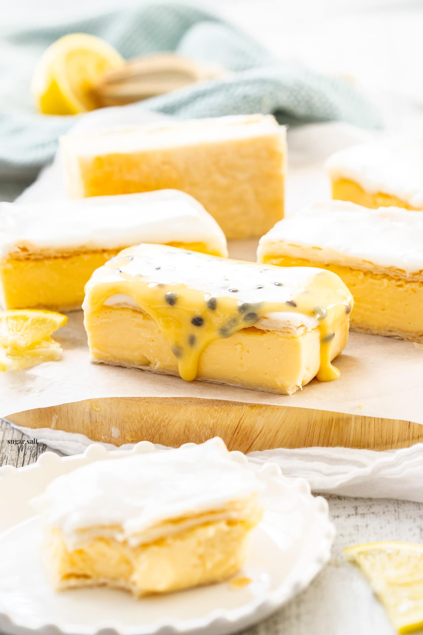 Slices of custard slice on a wooden board, the front one topped with passionfruit icing.