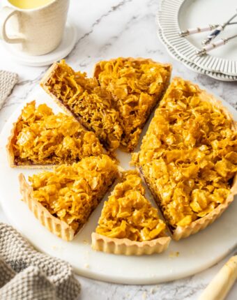 A cornflake tart with 5 slices cut from it.