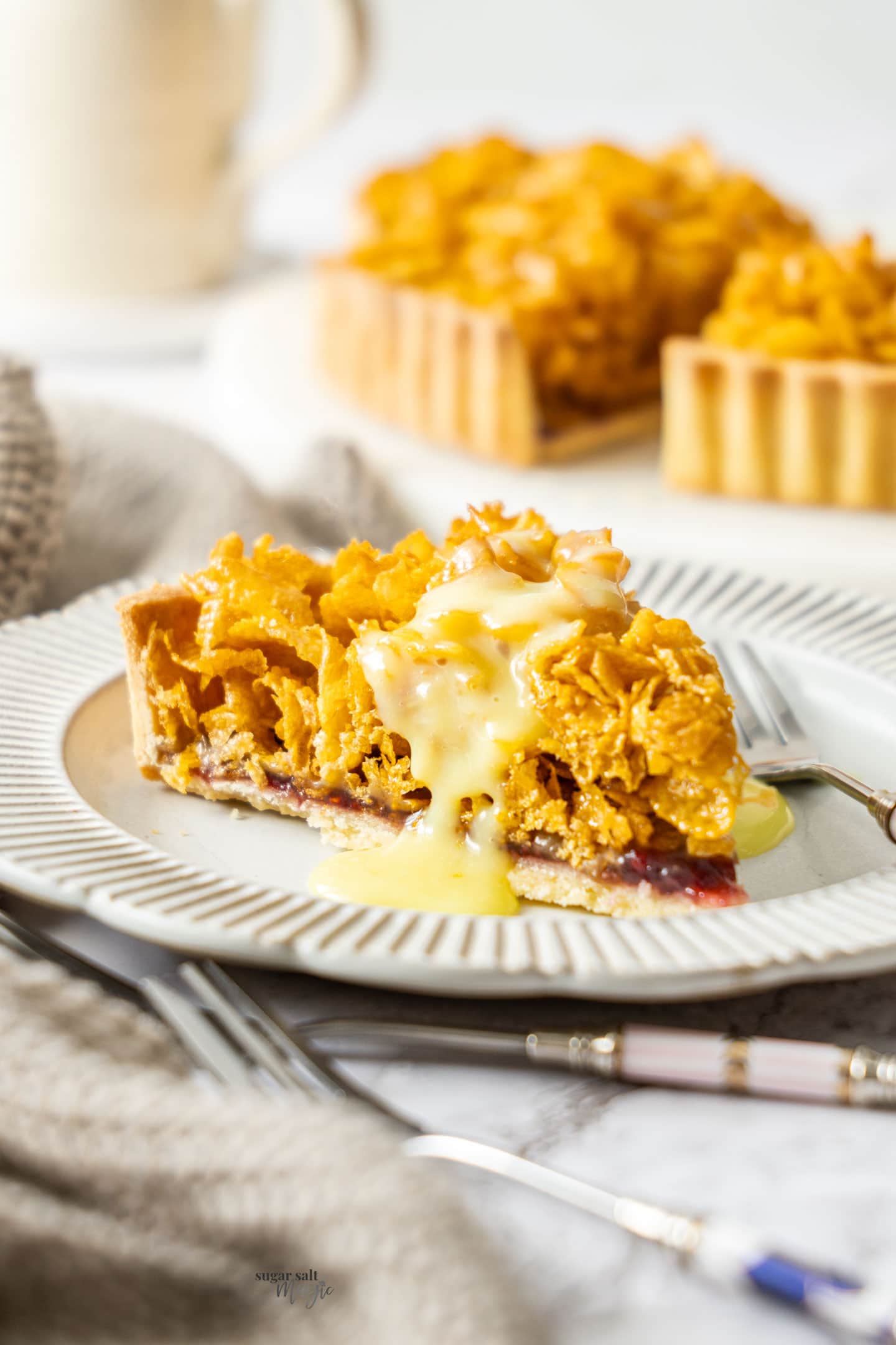 A slice of cornflake tart on a plate with custard dribbling down the side.