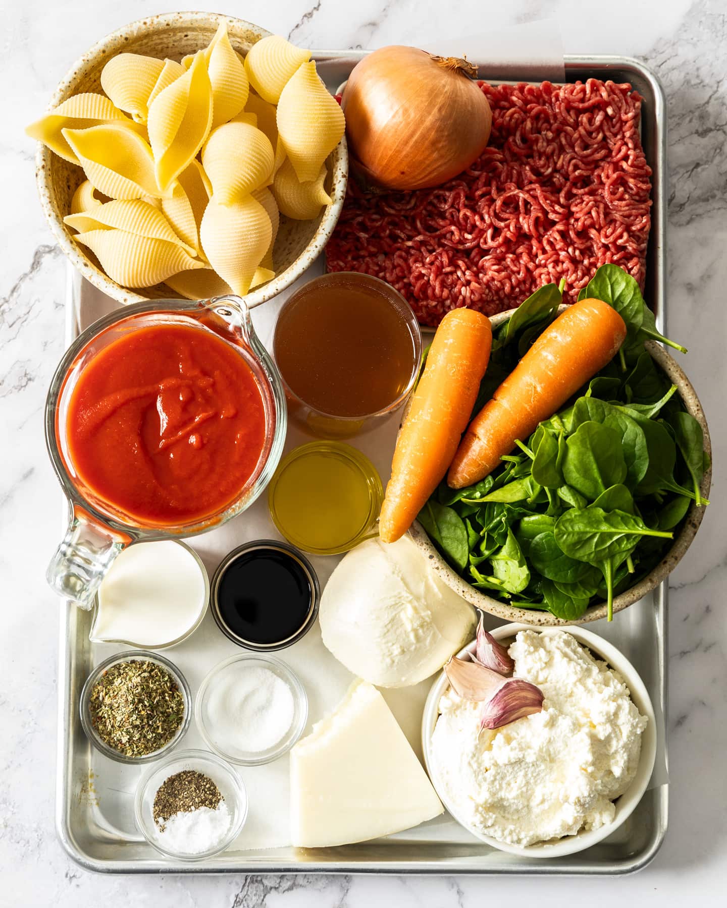 Ingredients for lasagna stuffed shells on a baking tray.