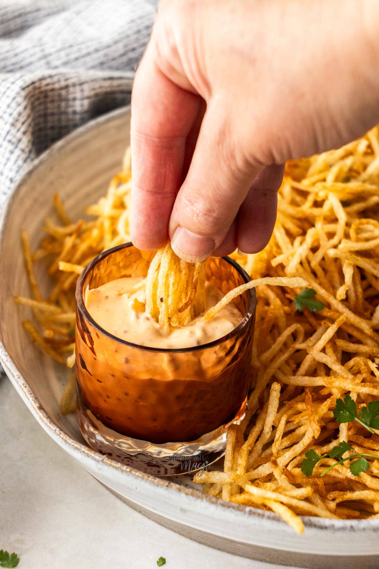Dunking a handful of fries into sauce.
