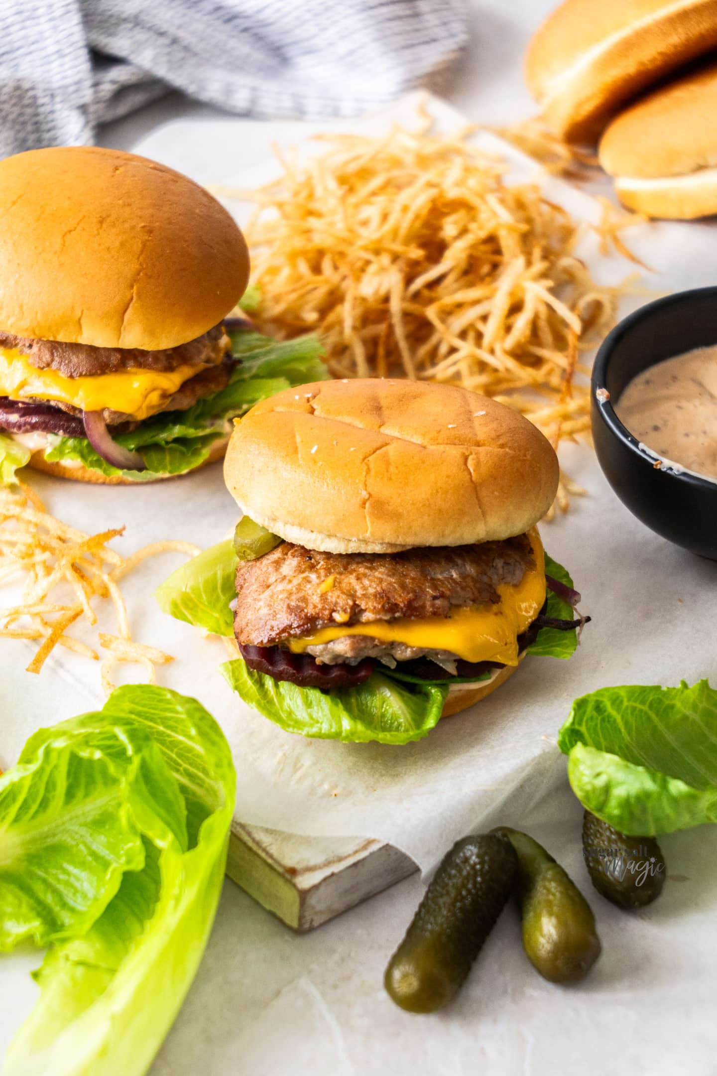 Two burgers on a platter with shoestring fries.