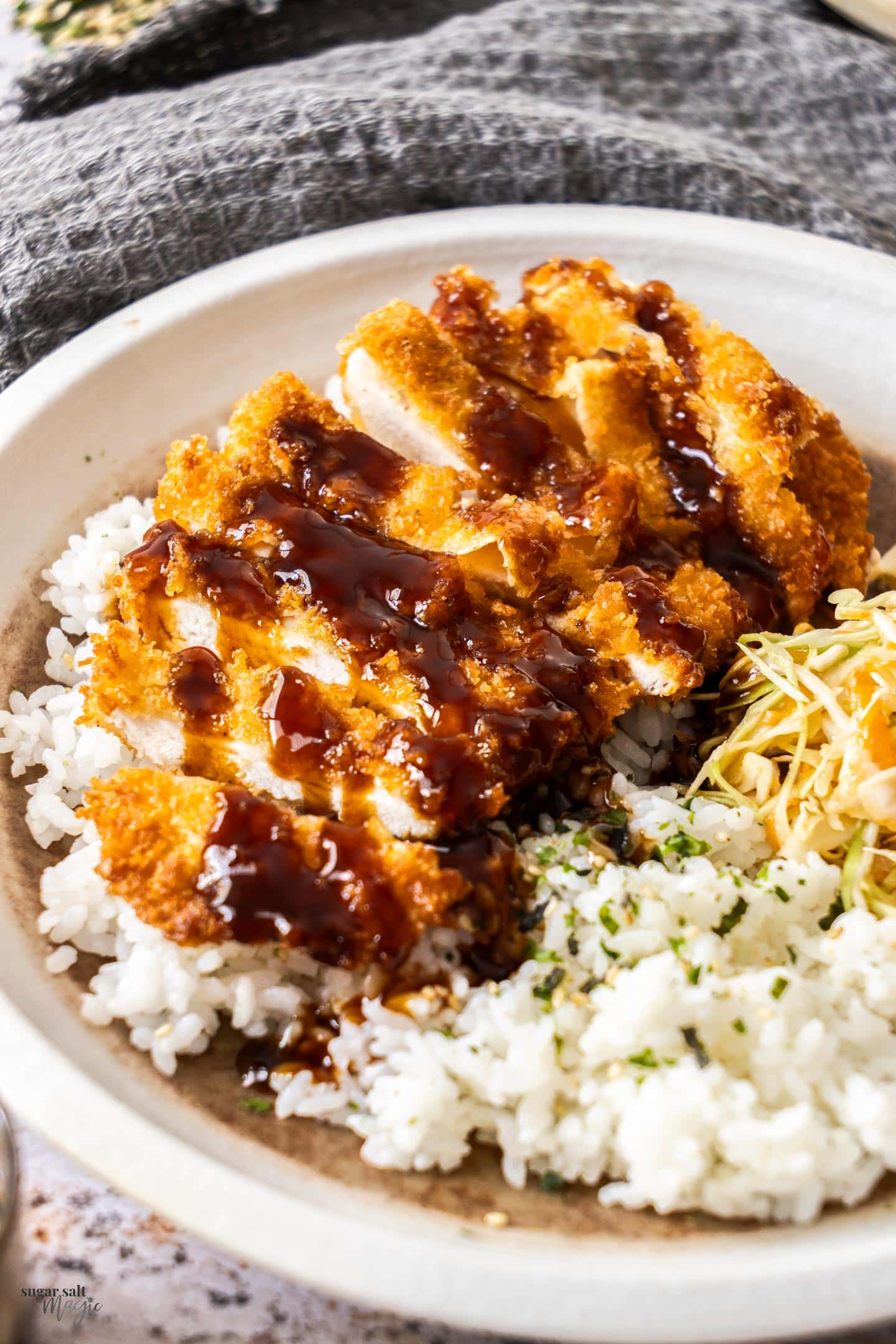Sliced chicken katsu on a bed of rice and cabbage.