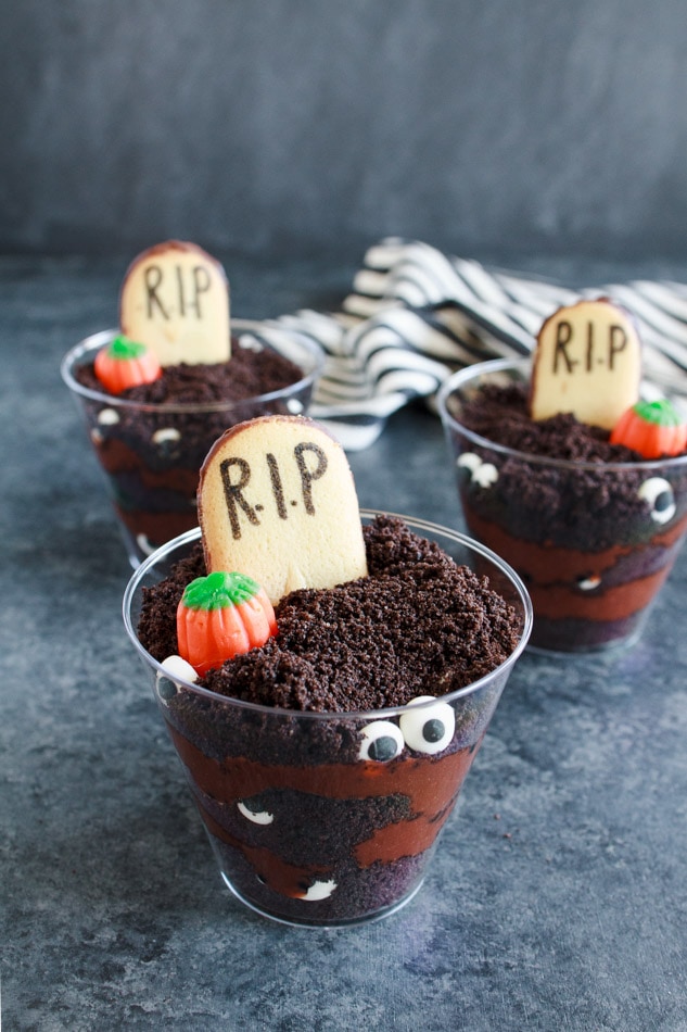 Graveyard pudding in small plastic cups with a cookie tombstone.