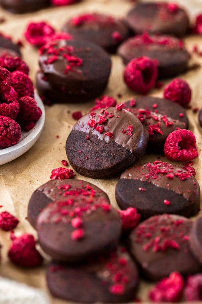 closeup: chocolate shortbread cookie recipe on a piece of parchment paper with freeze-dried raspberries scattered