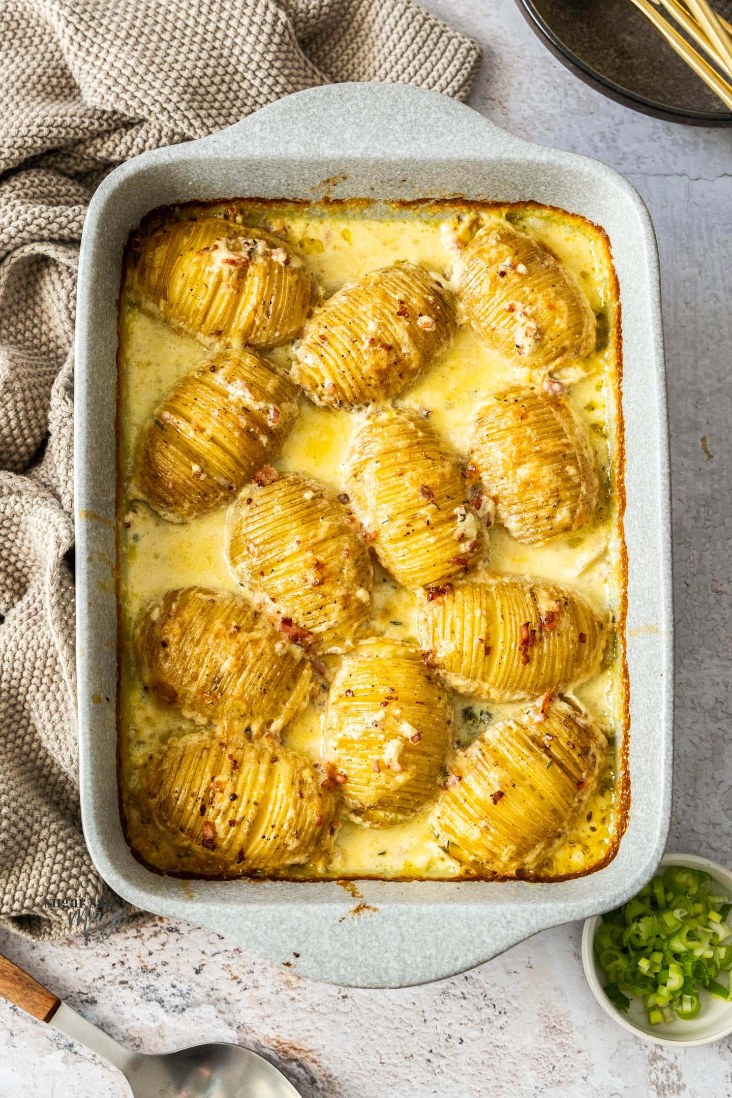 Roasted hasselback potatoes in cream in a casserole dish.