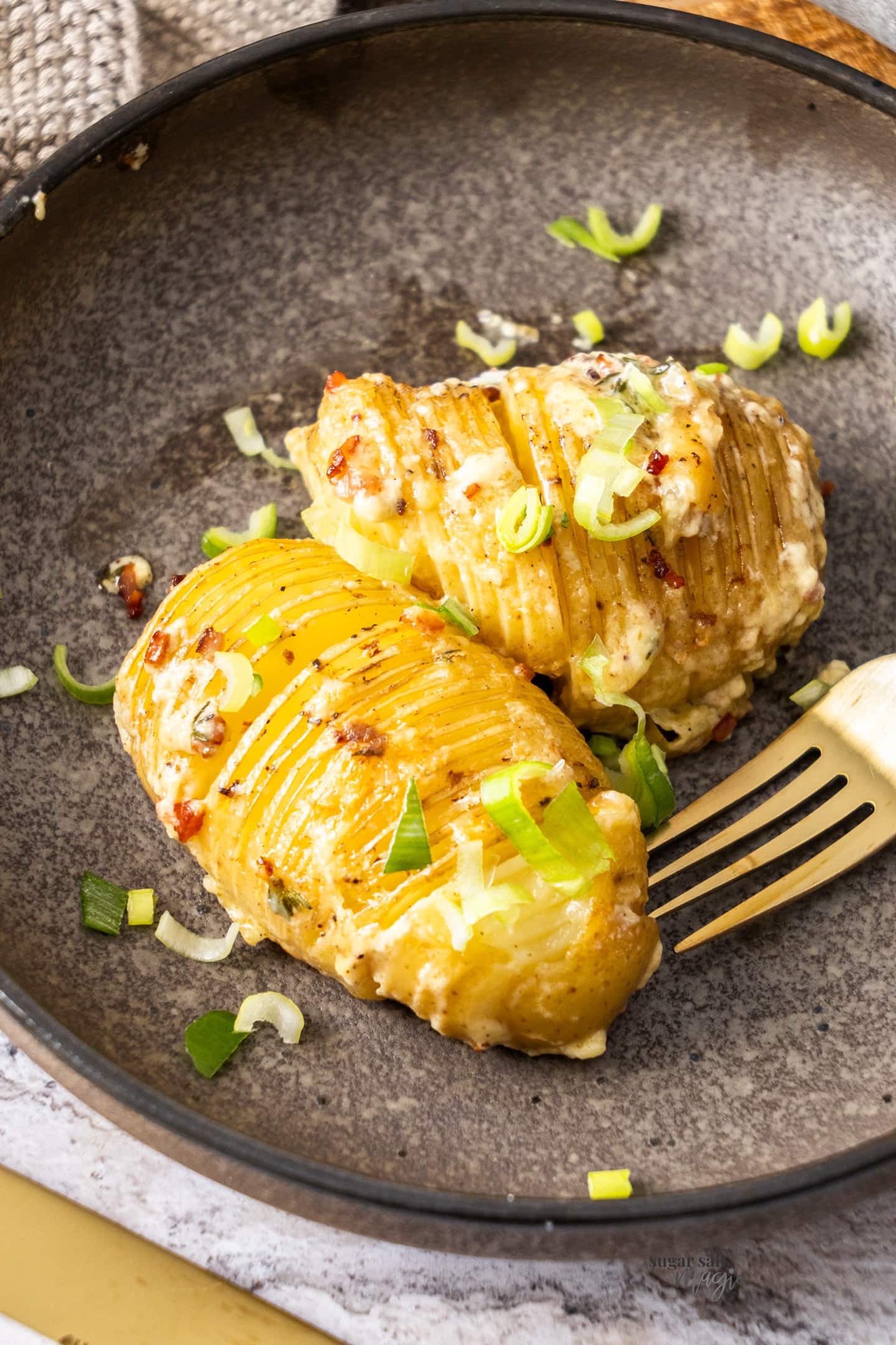 Two hasselback potatoes on a plate.