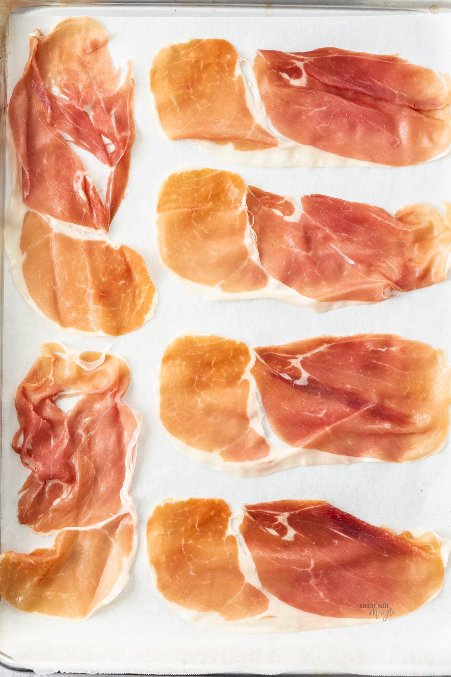 A baking tray with 6 slices of prosciutto laid flat.