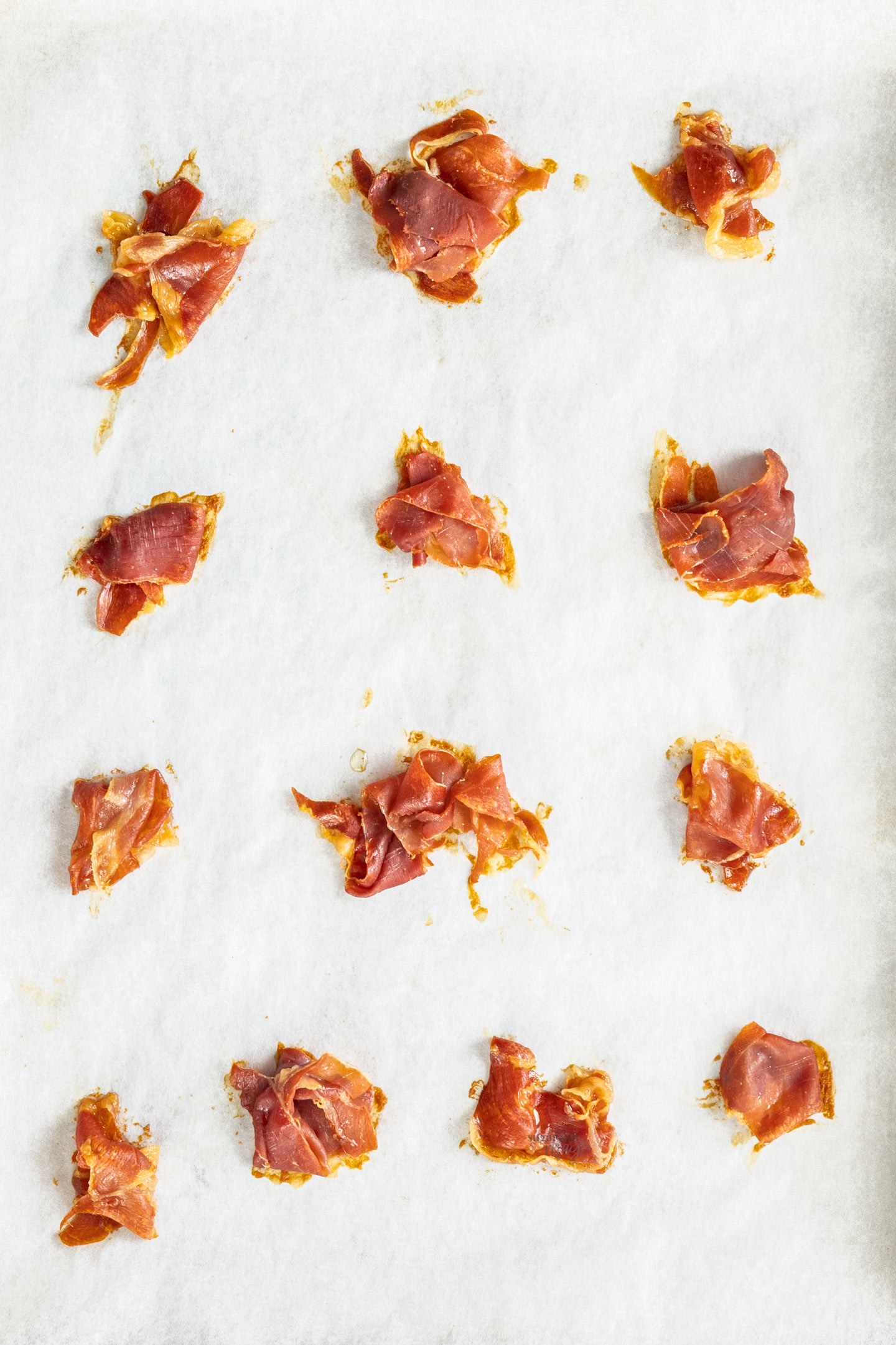 Small piles of crispy prosciutto on a baking tray.