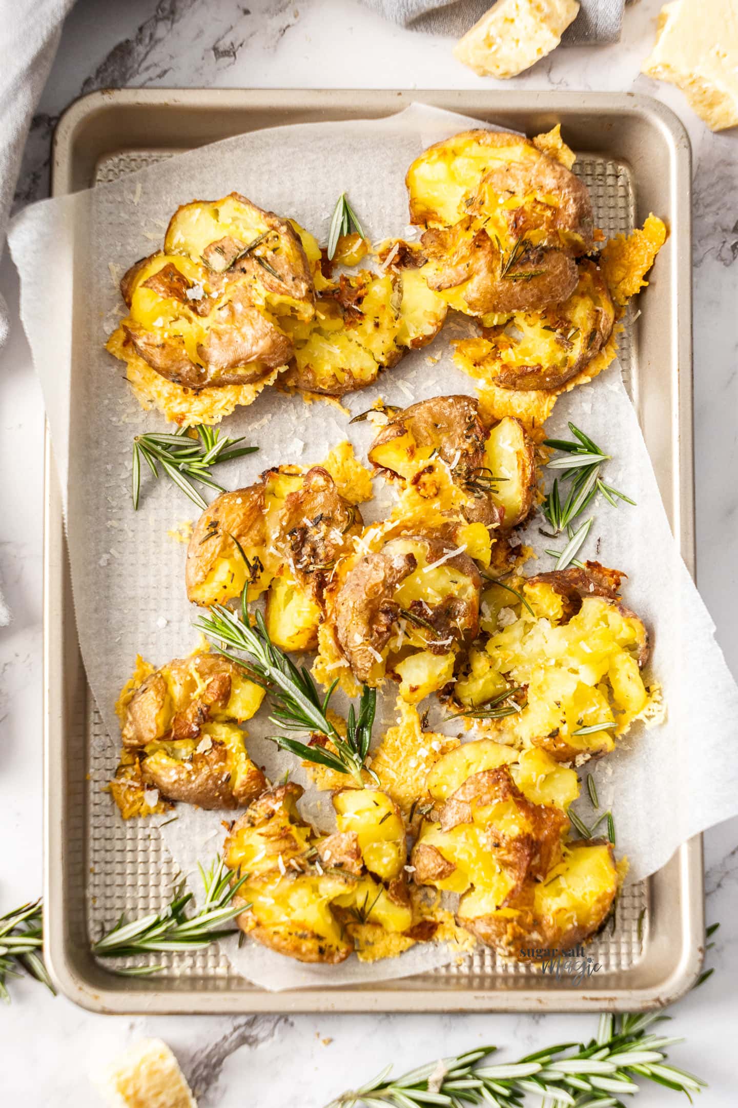 A baking tray loaded with parmesan smashed potatoes.