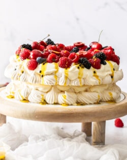 A two layer pavlova topped with berries on a cake stand.
