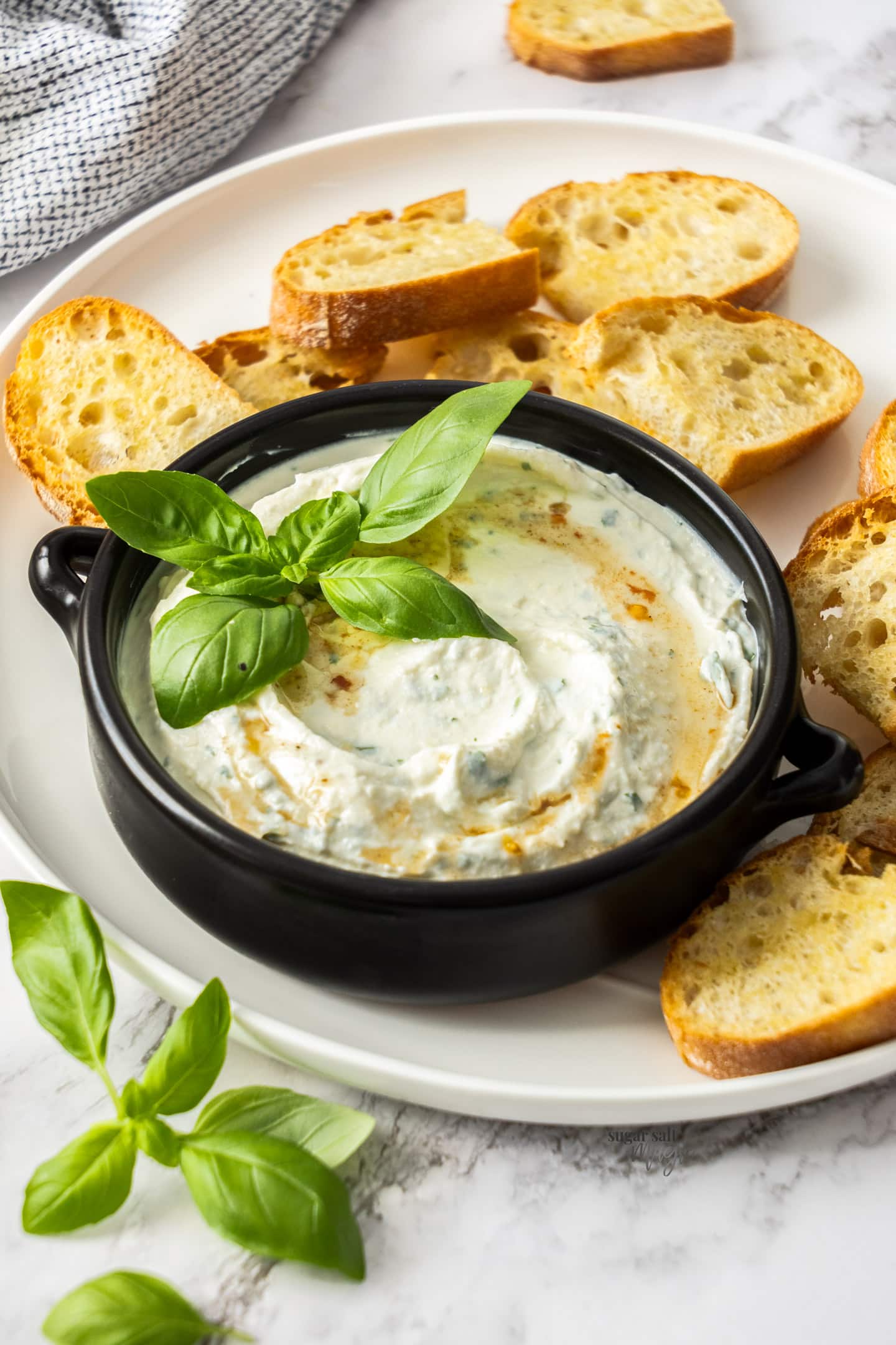 A bowl of ricotta dip surrounded by toasted bread.