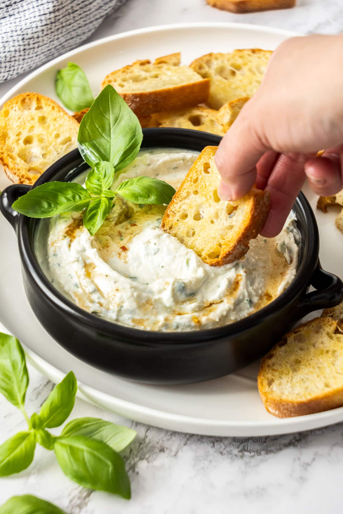 A piece of toasted bread being dipped into ricotta dip.
