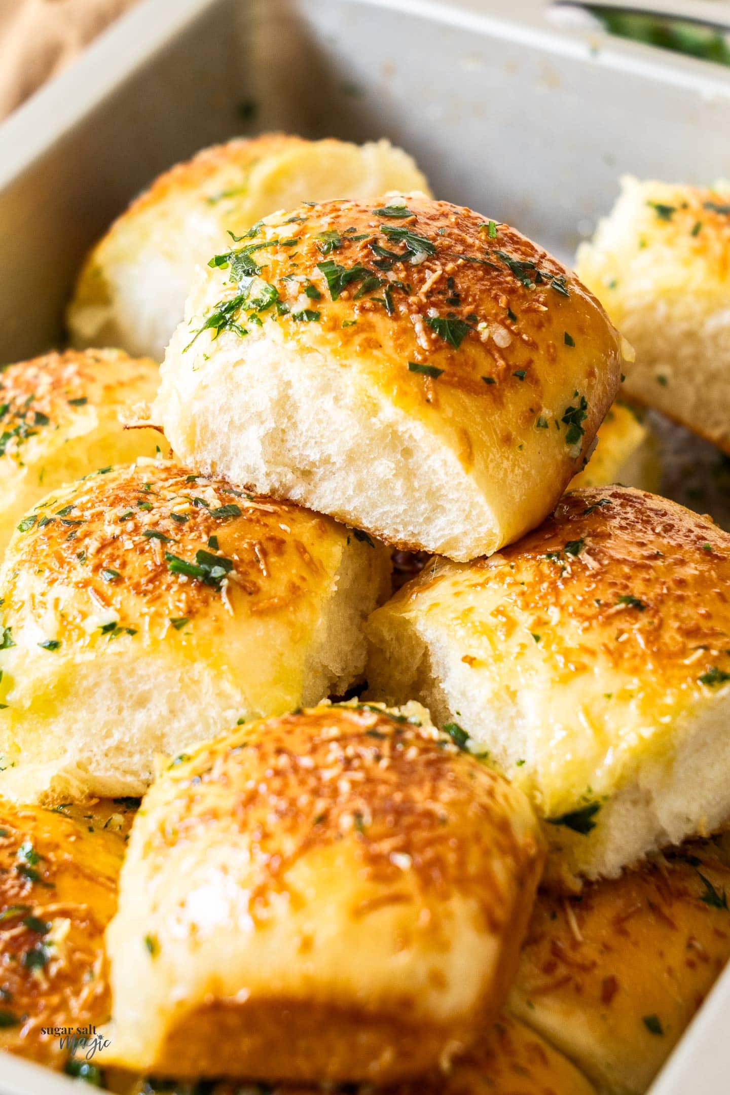 The garlic dinner rolls all piled up in a baking pan.